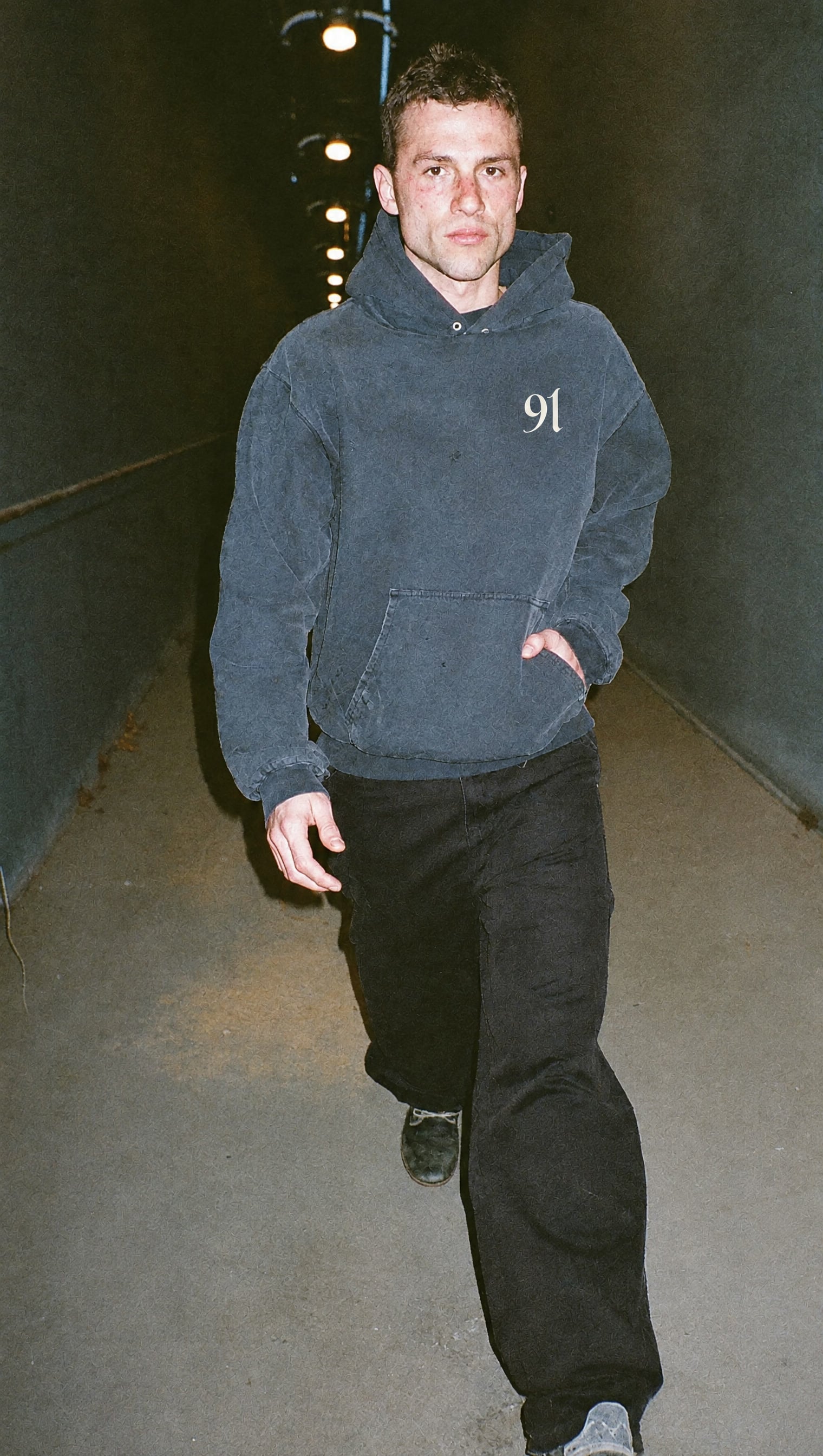 Washed navy heavyweight hoodie with the white 91 mark on the left chest, walking through pools of lamp light